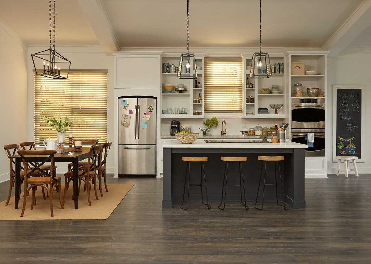 Modern kitchen that has motorized wood blinds showing partial light